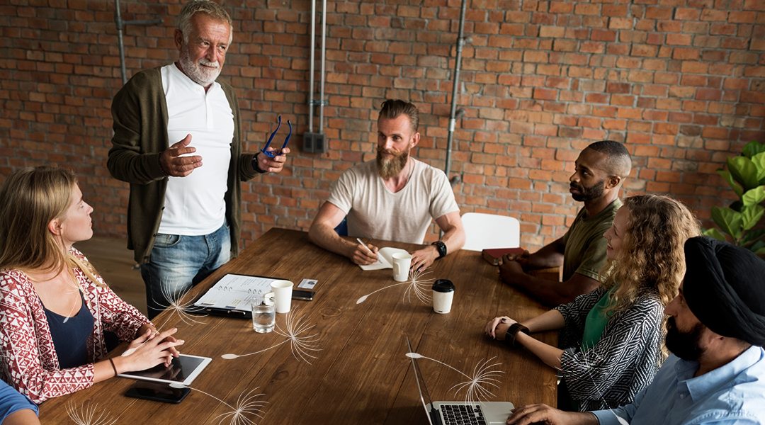 A diverse group of co-workers gathered around a table having a discussion.