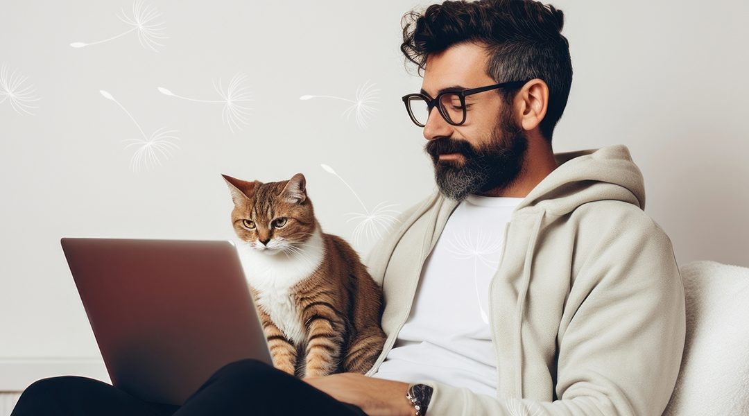 A man sitting on a couch with his cat and laptop working from home.