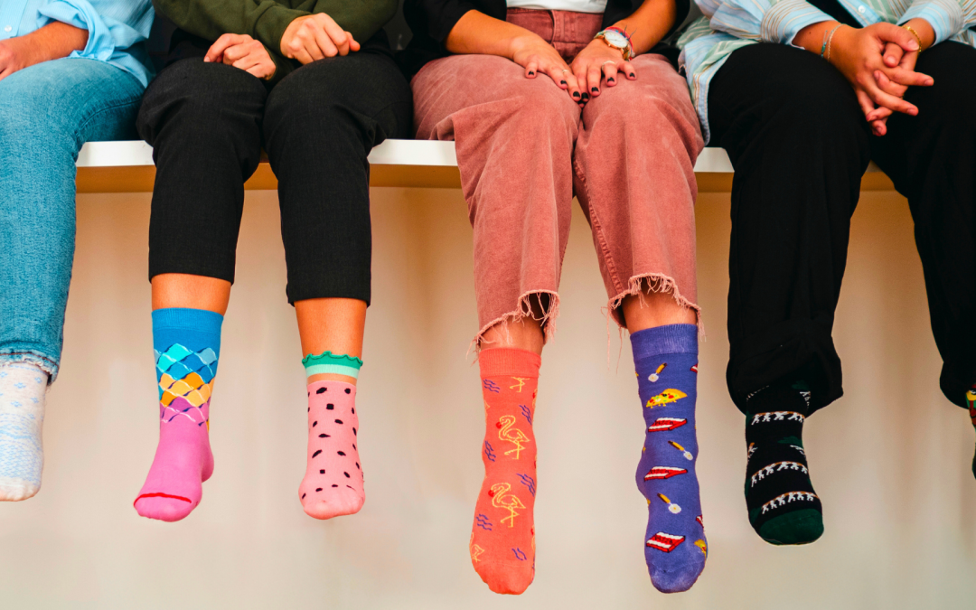 A group of bright mismatched socks on four people sitting.
